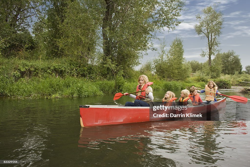 Siblings canoeing on river