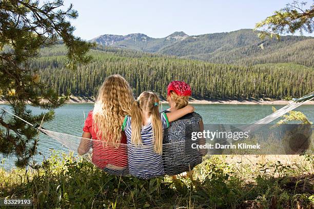 sister sitting on hammock together by lake - bozeman stock pictures, royalty-free photos & images