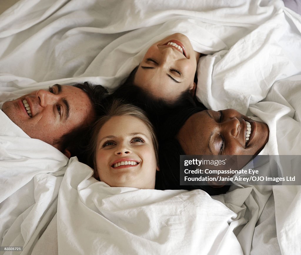 People wrapped in sheet on bed