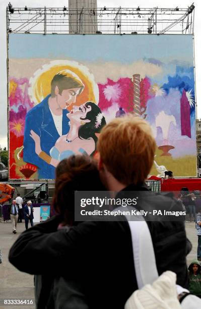 Young couple embrace in front of a giant painting which is being completed by Bollywood painters from India to celebrate the 'Festival of India in...