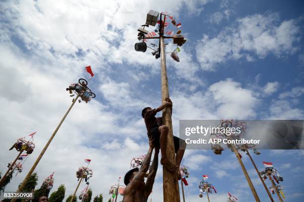 Child climbs a greased pole, on which prizes and flags are attached, to celebrate Indonesia's Independence Day in Denpasar on the Indonesian resort...