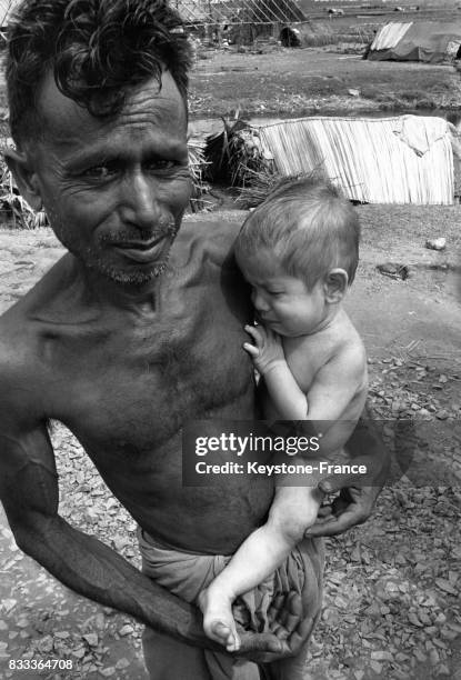 Portrait d'un homme tenant dans ses bras son bébé, dans un camp de réfugiés en Inde.