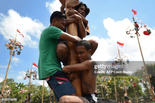 People take part in a competition to climb greased poles, on which prizes and flags are attached, to celebrate Indonesia's Independence Day in...