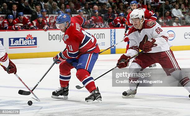 Saku Koivu of the Montreal Canadiens stickhandles the puck into the offensive zone against Peter Mueller of the Phoenix Coyotes at the Bell Centre on...