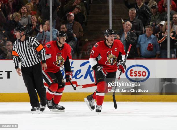 Daniel Alfredsson of the Ottawa Senators skates to the bench after scoring his first goal of the season followed by Jason Spezza of the Ottawa...