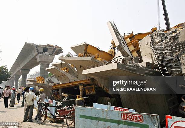 Workers gather at the site where a flyover bridge for the Delhi Metro collapsed in New Delhi on October 19, 2008. At least two people were killed and...