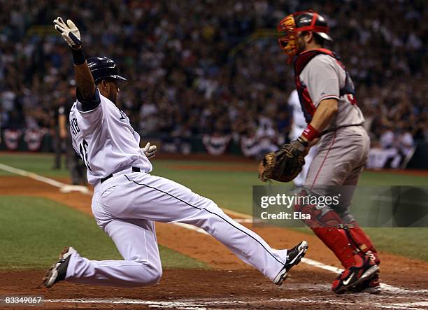 Willy Aybar of the Tampa Bay Rays slides in safely past catcher Jason Varitek of the Boston Red Sox to score a run in the fourth inning of game seven...