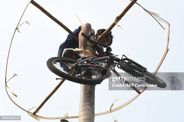 Participant collects a prize after making it to the top in Panjat Pinang, a pole climbing contest, as part of festivities marking Indonesia's 72nd...