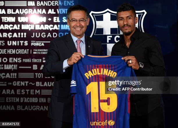 Barcelona's new Brazilian football player Paulinho Bezerra poses with his new jersey and Barcelona's president Josep Maria Bartomeu during his...