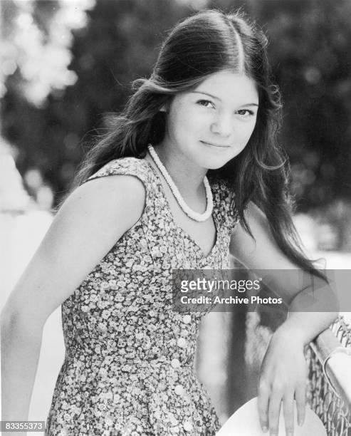 American actress Valerie Bertinelli leaning against a fence in a sun dress, 1970s.