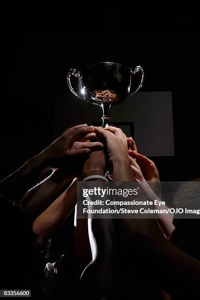 many hands holding up a silver trophy - teen awards stock pictures, royalty-free photos & images