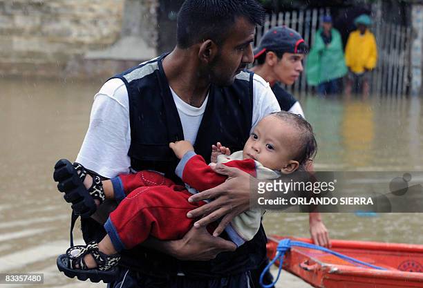 Member of the Honduran Red Cross carries a toddler during rescue operations after the overflowing of the Ulua river, in the municipality of El...