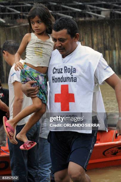 Member of the Honduran Red Cross carries a girl during rescue operations after the overflowing of the Ulua river, in the municipality of El Progreso,...