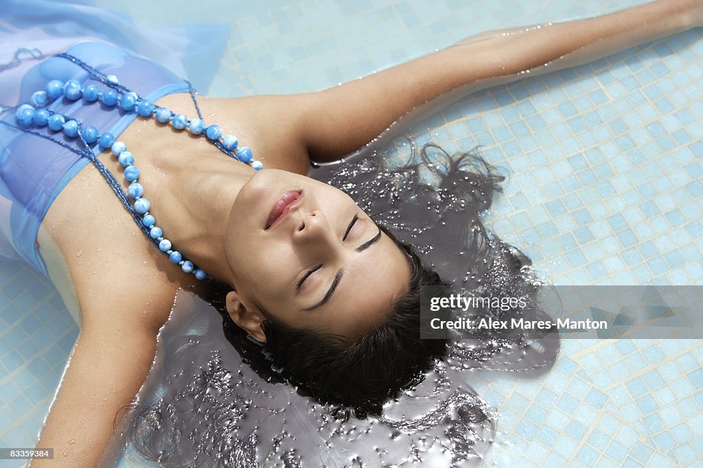 Young woman lying face up in pool