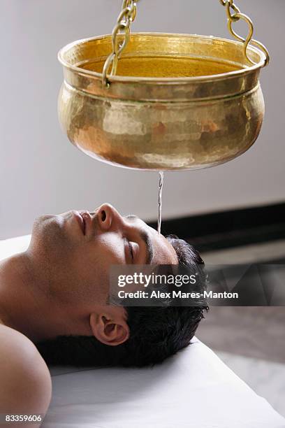 young man having ayurvedic spa treatment - shirodhara stock pictures, royalty-free photos & images