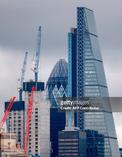 Construction cranes stand near skyscrapers in the City of London, including 30 St Mary Axe, commonly called the "Gherkin", and the Leadenhall...