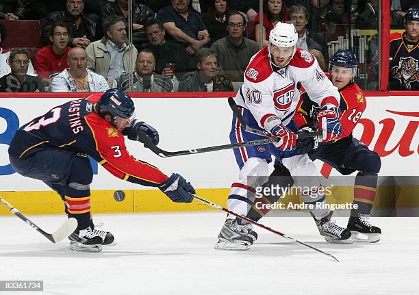 Maxim Lapierre of the Montreal Canadiens chips the puck past Karlis Skrastins and Ville Peltonen of the Florida Panthers at the Bell Centre on...