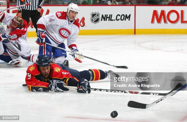 Stephen Weiss of the Florida Panthers reaches for a loose puck while lying on his stomach as Roman Hamrlik of the Montreal Canadiens looks on at the...