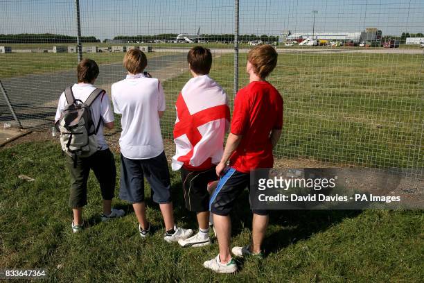 Four England fans watch through the secruity fence at Stansted Airport as the plane carrying the England squad arrives back from Germany. Picture...