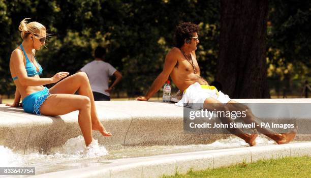 Vistors cool off their feet in the Princess Diana Memorial Fountain, in Hyde Park, in central London.