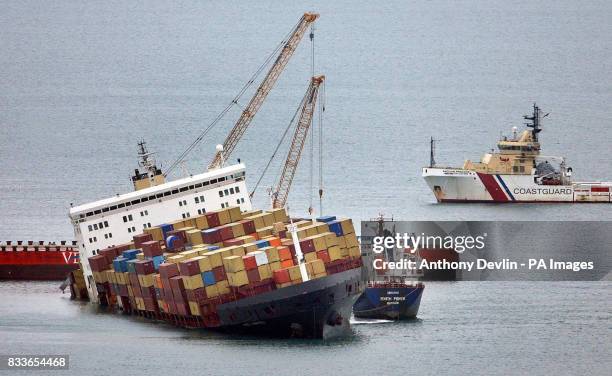 Barge carrying large cranes moors alongside the grounded cargo ship MSC Napoli as it sits a mile off the coast near Sidmouth, Devon.