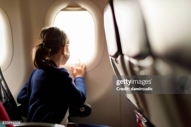 cute little girl traveling by an airplane - girl traveler stock pictures, royalty-free photos & images