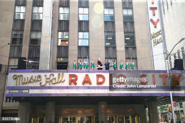Man in Santa Claus costume and PLJ announcer John Foxx along with the Rockettes pose as The Radio City Rockettes Christmas In August 2017 perform on...
