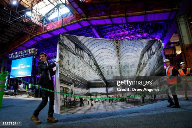 Aides to New York Governor Andrew Cuomo move a rendering of the Moynihan Train Hall before the start of a press event to mark the beginning of the...