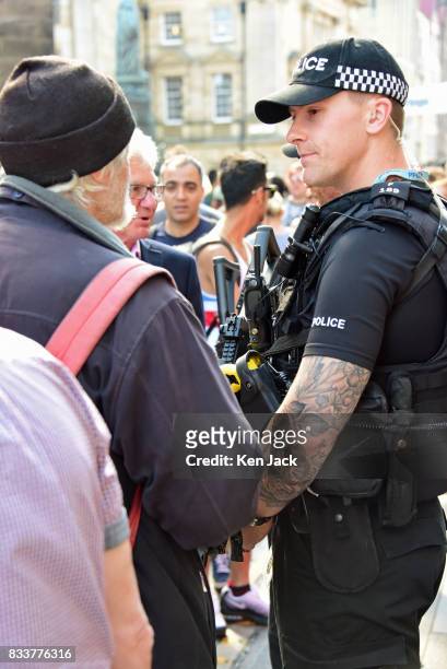 An armed police officer chats to a passer-by on the Royal Mile during the Edinburgh Festival Fringe where security has this year been stepped up, on...
