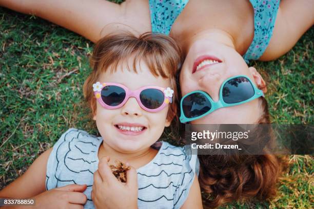 公園と笑顔で草の上に横たわってかわいい女の子 - familys the lying game season two ストックフォトと画像