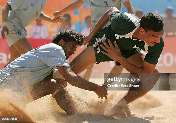 Tajammal Muhammad of Pakistan is tackled by India during their beach kabaddi match on day five of the 2008 Asian Beach Games at Nusa Dua Beach on...