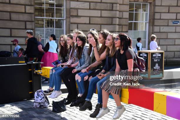 Group of girls sit on a security barrier blocking the entrance to the Royal Mile during the Edinburgh Festival Fringe where security has this year...