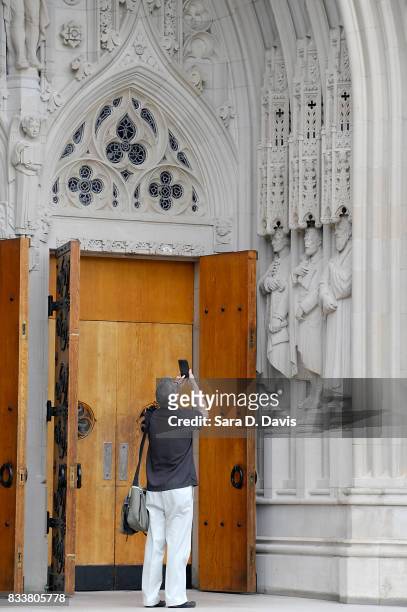 Passerby stops to take a mobile phone photo of a statue on the portal of Duke University Chapel, seen here in middle right, bearing the likeness of...