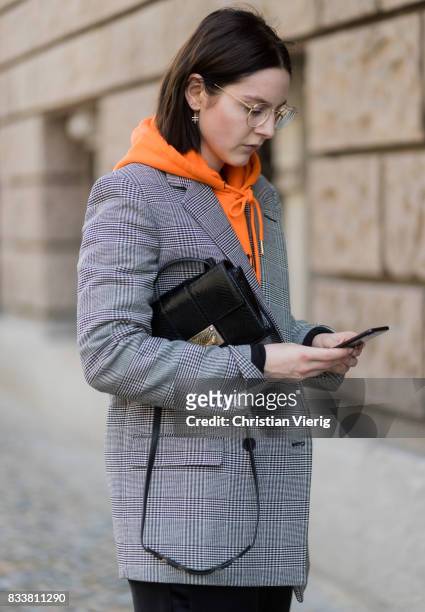 Maria Barteczko wearing orange hoodie Wasted Paris, oversized checked blazer in grey Stella McCartney, wide leg black trousers H&M, black heels...