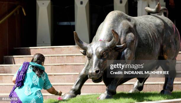 Sub-broker makes flower offerings before the statue of a bull outside the Bombay Stock Exchange ahead of trading in Mumbai on October 22, 2008....