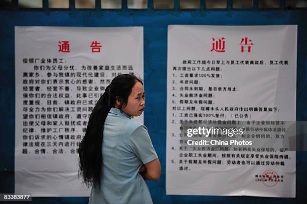 Worker reads a notice about the township government will offer payment for the time being to sacked workers, as the boss has run away, in the Junling...