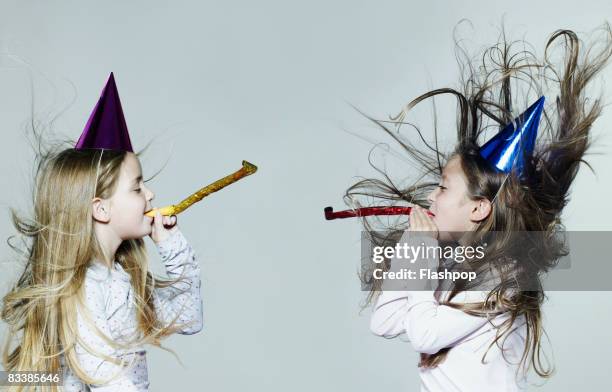 portrait of two girls wearing party hats - party blower stock pictures, royalty-free photos & images