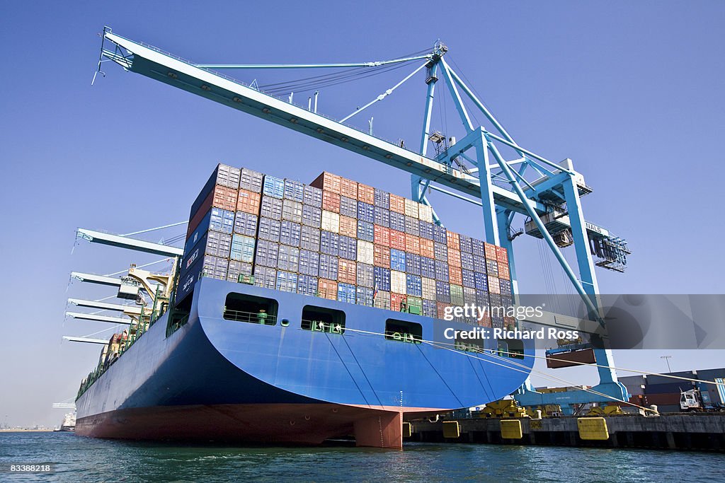 A boat carrying cargo with cranes for lifting up c