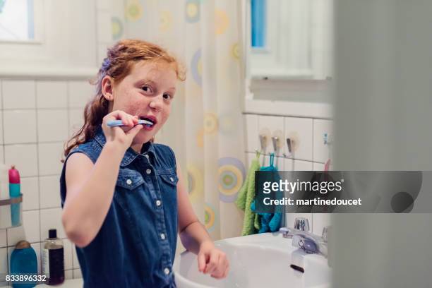 Young redhead girl brushing teeth on school morning.