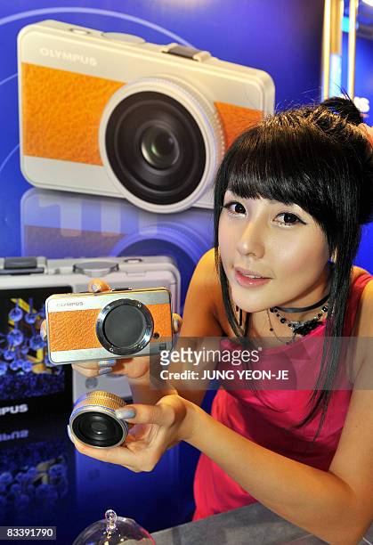 South Korean model poses with a mock-up of Japanese optical giant Olympus' new interchangeable lens type digital camera based on the 'Micro Four...