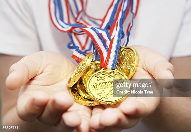 boys hands held out full of gold medals - médaillé photos et images de collection