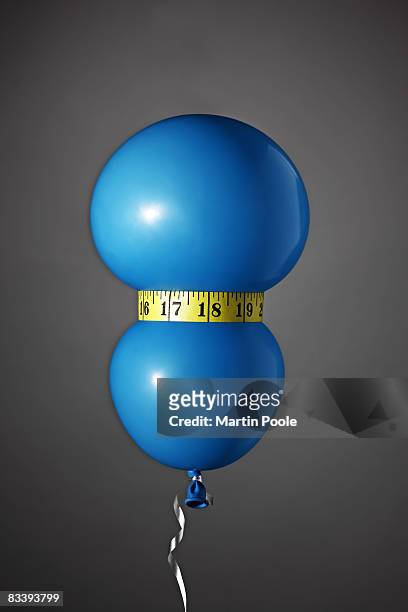 balloon being squezzed around waste with tape  - measuring tape stockfoto's en -beelden