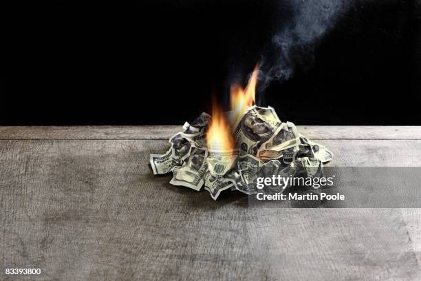 pile of 100 dollar notes on table on fire - spending stock pictures, royalty-free photos & images