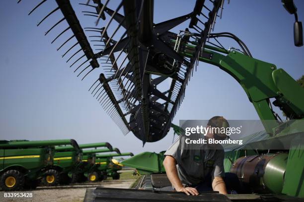 Worker performs maintenance on a Deere & Co. John Deere combine harvester at the Smith Implements Inc. Dealership in Greensburg, Indiana, U.S., on...