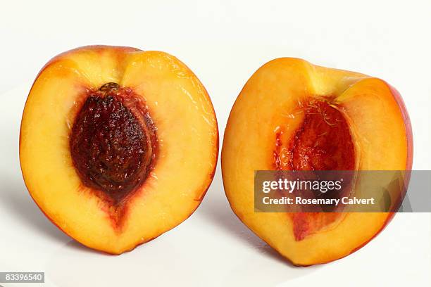 ripe nectarine cut in half to reveal the stone. - juicy stock pictures, royalty-free photos & images
