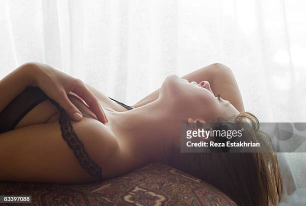 young woman in lingerie lays back on ottoman - alluring fotografías e imágenes de stock