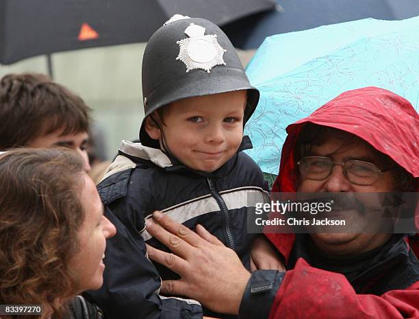 Young boy in a British Policeman's hat prepares to greet HRH Queen Elizabeth II as she takes part in a walk about in the Main Square on the first day...