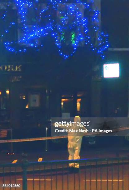Police forensic expert standing under Christmas lights near a murder scene on Upper Street, Islington, London, where two youths were stabbed. One...