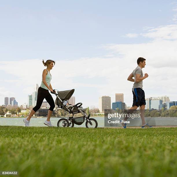 couple jogging with a baby stroller - three wheeled pushchair stock pictures, royalty-free photos & images