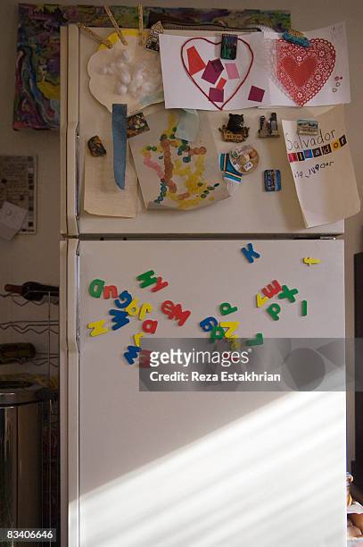 refrigerator door with child's school art projects - letra magnética fotografías e imágenes de stock